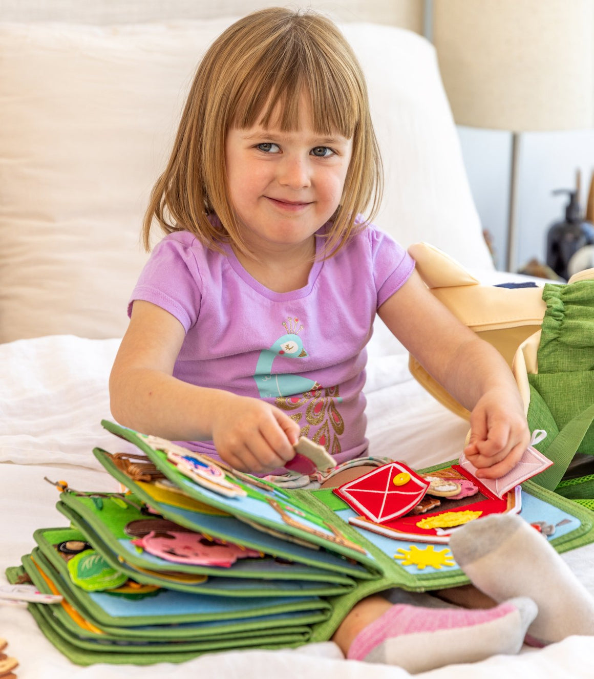 toddler girl playing with colorful MyFirstBook fabric busy book with interactive elements