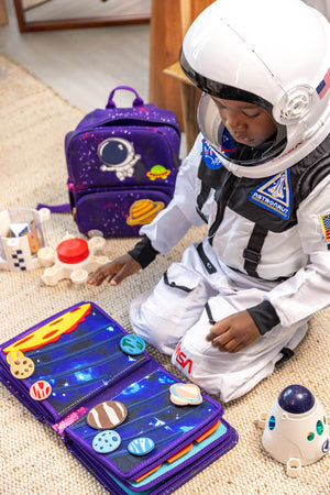 Boy dressed as an outer space astronaut playing with My First Book Space busy book, engaged in the Montessori inspired play and sensory activities. Makes a great baby gift.