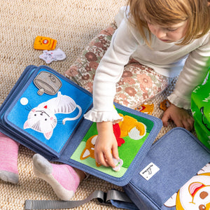 Young girl playing with My First Book Pet Friends busy book, showing she is focusing with the Montessori style sensory play. Makes a great baby gift.