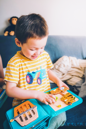 A boy happily playing cat sensory book, featuring montessori play and practicing sensory and fine motor skills. Makes great baby gift.