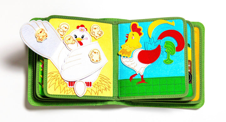 MyFirstBook fabric busy book open showing hen with chicks page and rooster page with colorful interactive elements