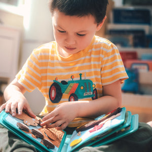 A boy plays with the My First Book Nordic Forest busy book, fully engaged in Montessori-inspired play and sensory activities. A perfect baby gift for curious minds.