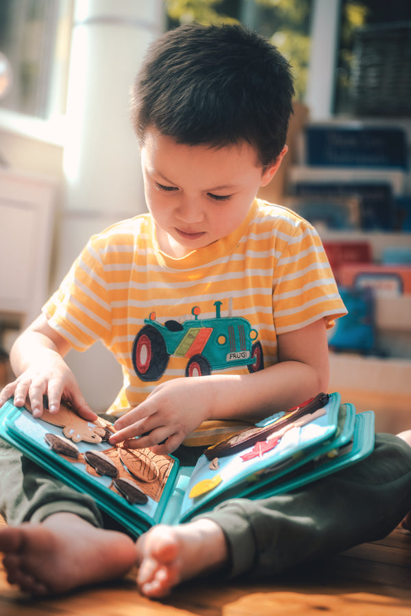 A boy plays with the My First Book Nordic Forest busy book, fully engaged in Montessori-inspired play and sensory activities. A perfect baby gift for curious minds.