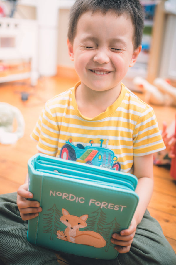 A boy being so happy after receiving My First Book Nordic Forest Montessori  busy book as a baby gift.