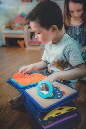 Photo of child building sensory skills and exploring imaginative play with the Montessori inspired My First Book Space busy book. Makes a great baby gift.