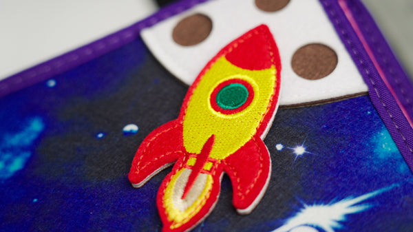 Close up image of Space busy book, featuring some of the high quality textures, spaceships, and other outer space sensory features that inspire Montessori learning. Makes a great baby gift.
