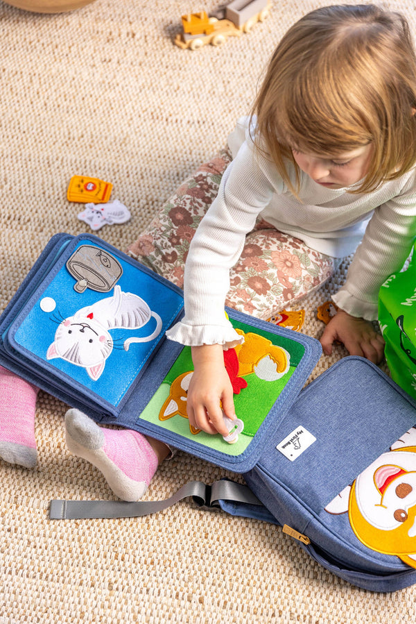 Young girl playing with My First Book Pet Friends busy book, showing she is focusing with the Montessori style sensory play. Makes a great baby gift.