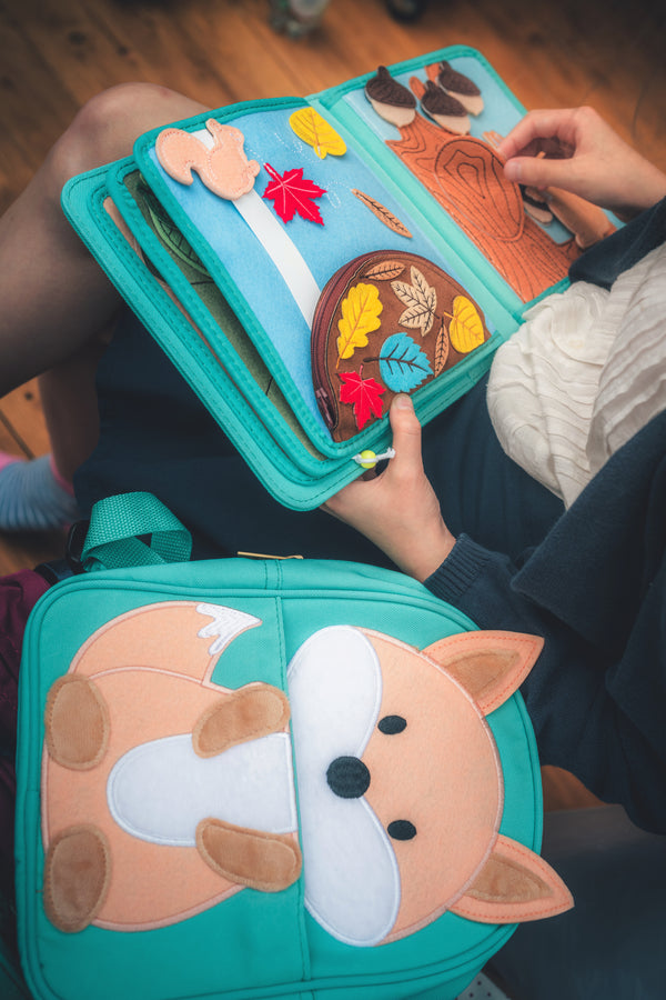 A girl reading My First Book Nordic Forest busy book, fully engaged in Montessori-inspired play and sensory activities and creating stories.