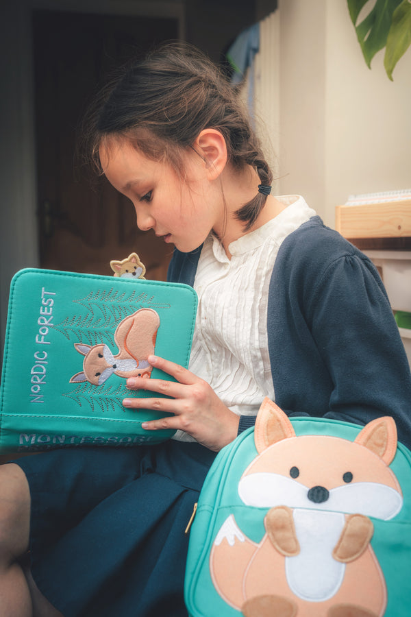 A girl is reading the My First Book Nordic Forest busy book, creating stories while practicing sensory activities. A perfect baby gift for curious minds.