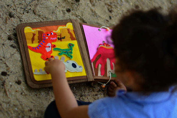 A young child builds sensory skills through Montessori inspired play using the My First Book Dinosaur busy book. Makes a great baby gift.