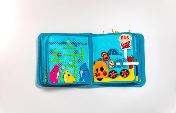 Two pages of My First Book Baby Shark busy book product photo, showing the cute characters and sensory interactive play in this Montessori inspired book. Makes a great baby gift.